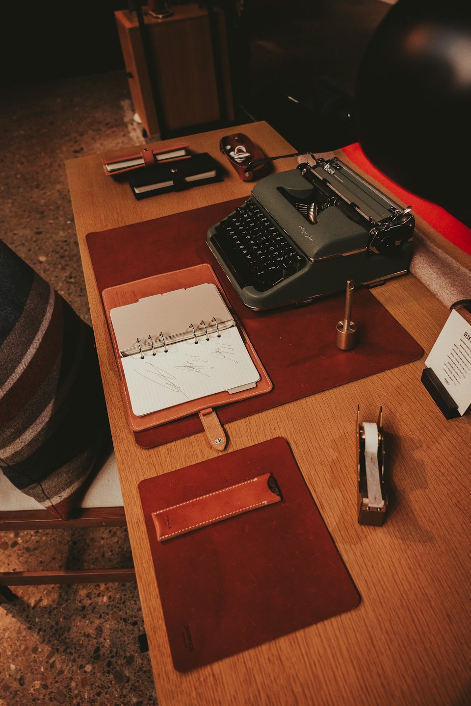 Macchina da scrivere vintage e cancelleria in pelle disposti su una scrivania di legno.